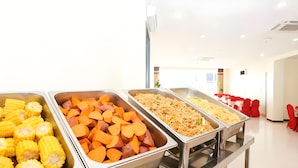 Een buffet met schalen vol maïs, zoete aardappelen en noedels.