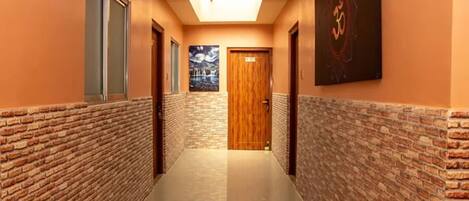 A hallway with brick walls, a polished floor, and a wooden door at the end.