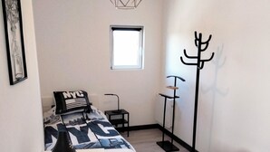A bedroom with a bed, a desk, a coat rack, and a window. - Apartment for up to 6 people (Pléboulle)
