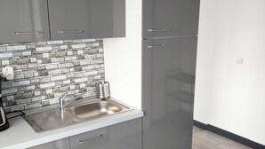 A modern kitchen with grey cabinets, a stainless steel sink, and a tiled backsplash. - Apartment for up to 6 people (Pléboulle)