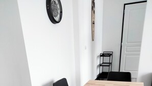 A conference room with a rectangular wooden table, black chairs, a clock on the wall, and a door in the background. - Apartment for up to 6 people (Pléboulle)