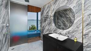 Un baño moderno con pared de mármol, espejo redondo y lavamanos negro.