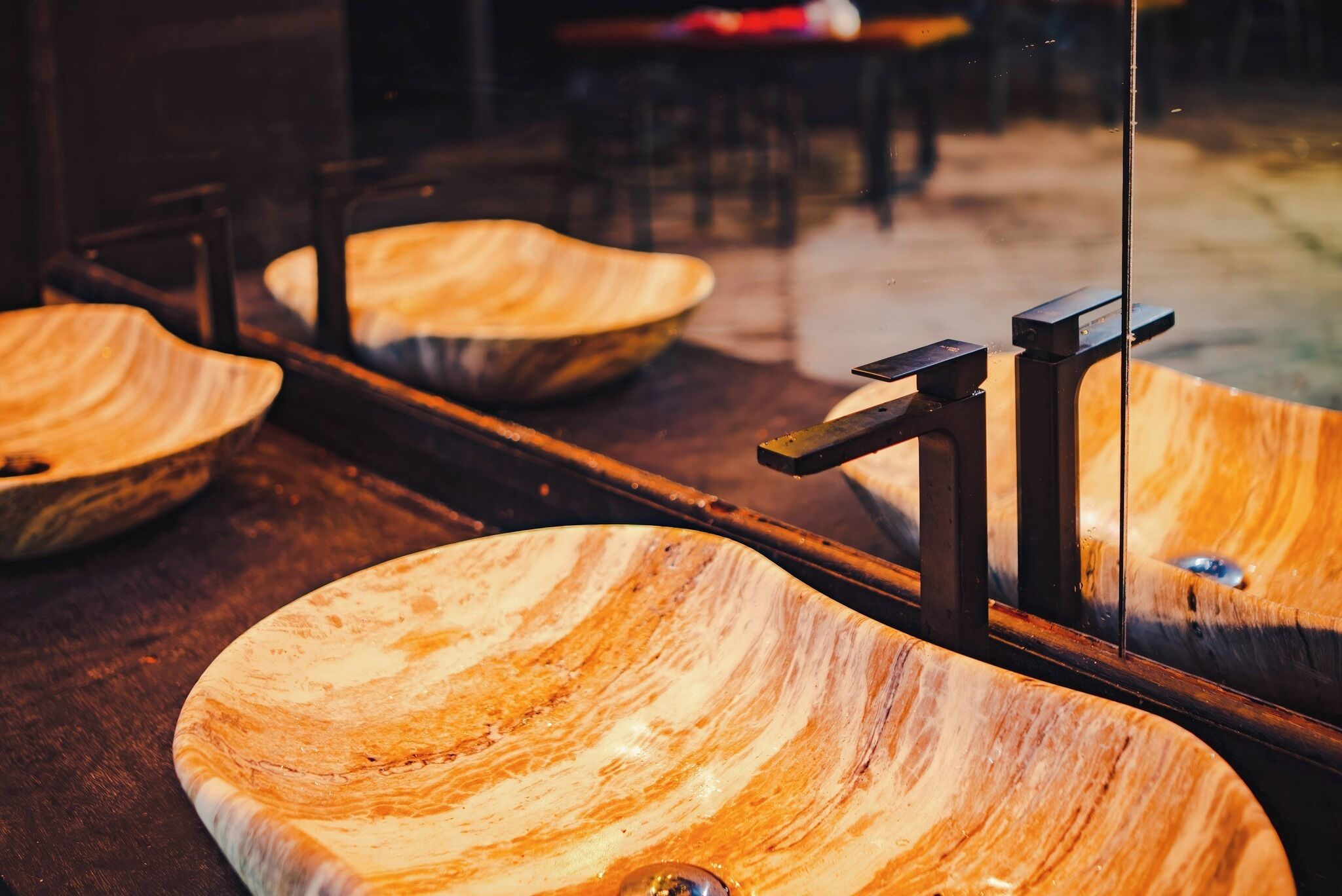 Un lavamanos de madera con forma de cuenco y superficie reflectante.