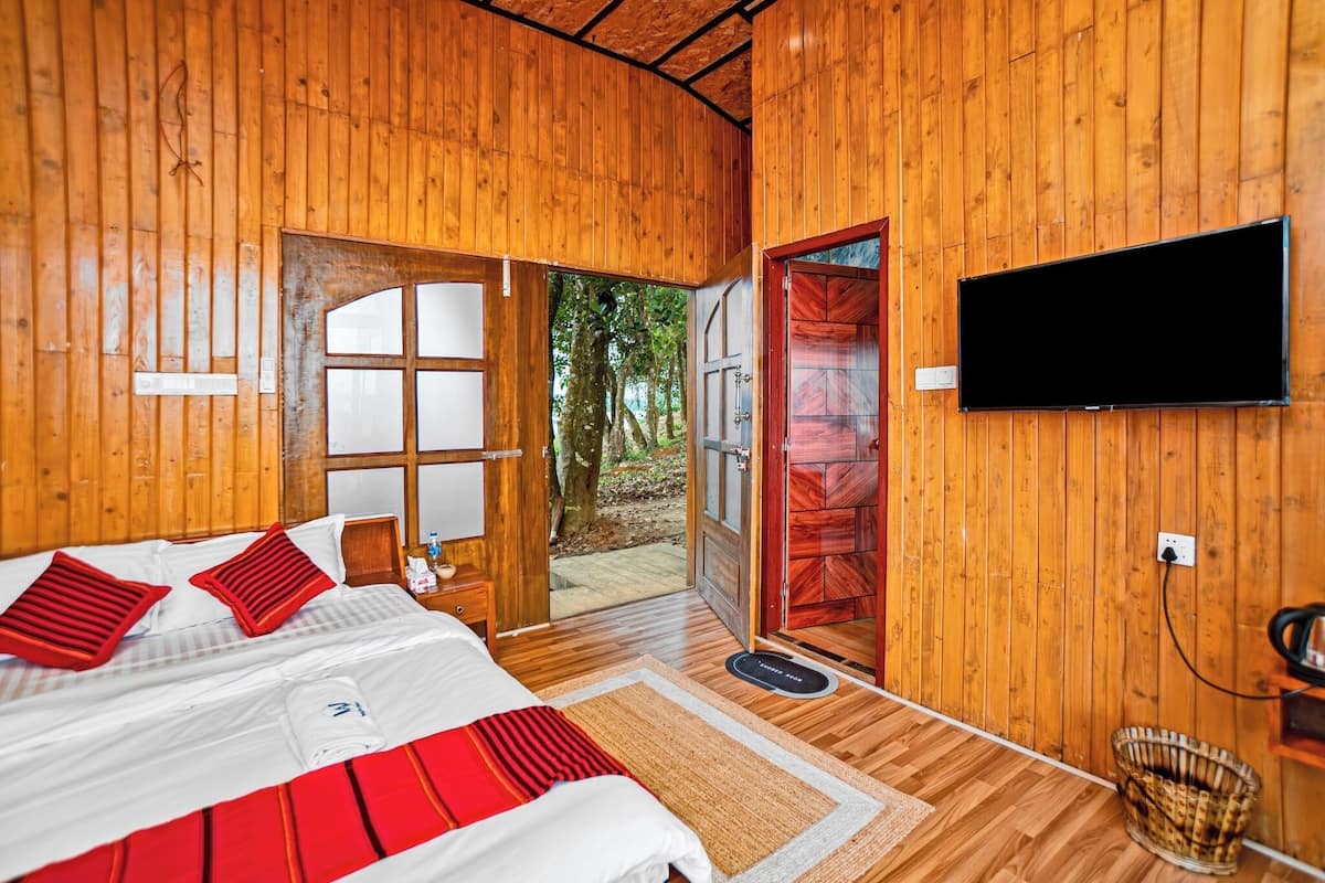 Une pièce en bois avec un lit, un téléviseur et une porte donnant sur l’extérieur.