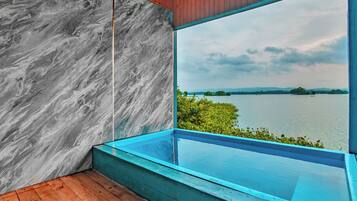 A modern room with a large window overlooking a lake, a wooden floor, and a marble wall.