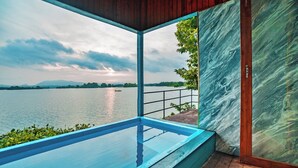 Piscina moderna al aire libre con vistas despejadas a un lago y montañas distantes.