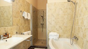 Un bagno con una vasca da bagno ampia, una zona doccia e due lavandini.