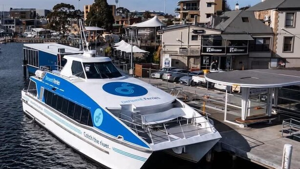 Un ferry atracado en un muelle, con un paisaje urbano al fondo.