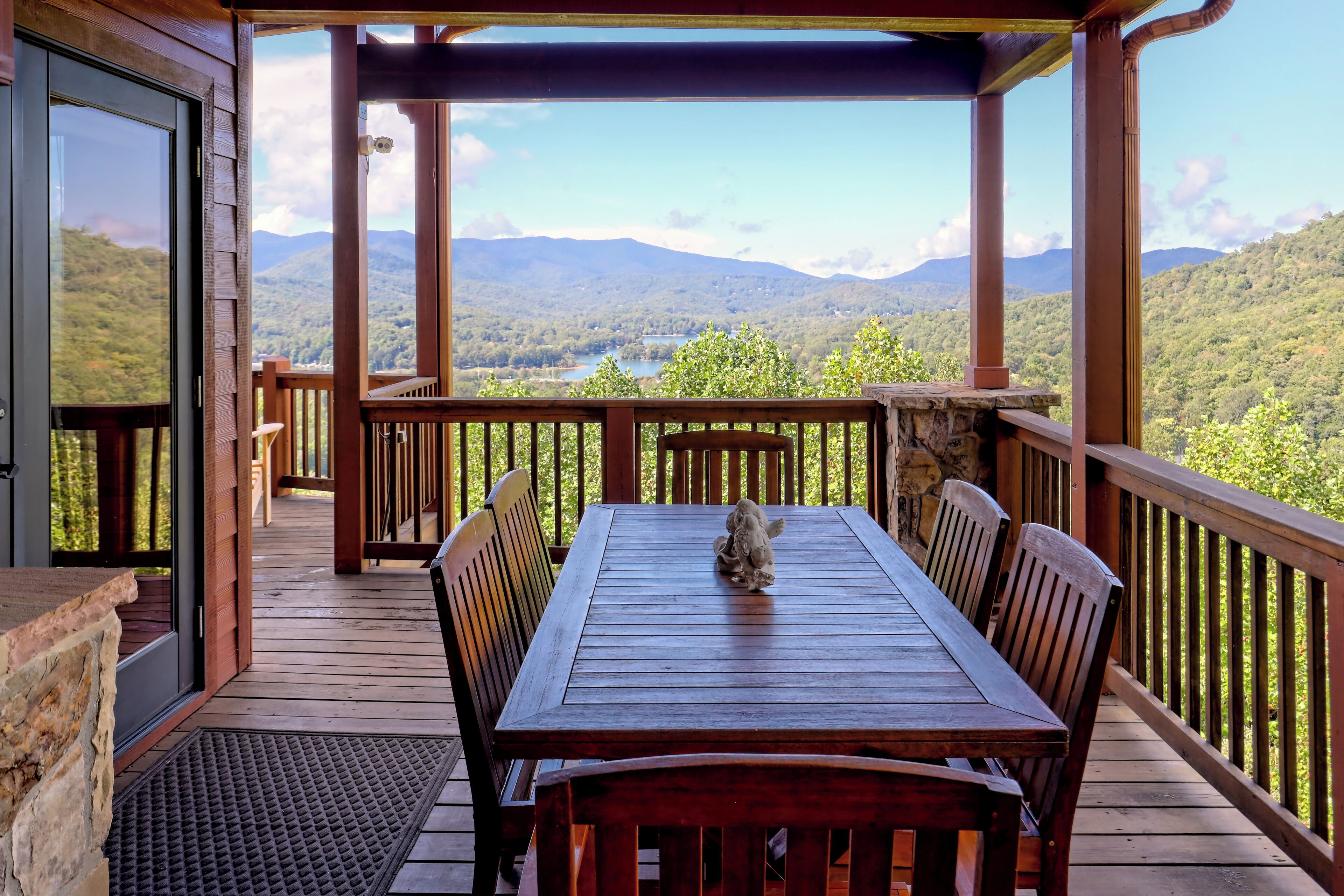 Une terrasse en bois avec une table et des chaises, offrant une vue sur un paysage montagneux.