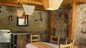 A rustic wooden room with a bed, wooden chairs, a table, and a stone wall.