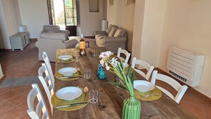 Un comedor con una mesa de madera rústica dispuesta para seis personas, rodeada de sillas blancas.