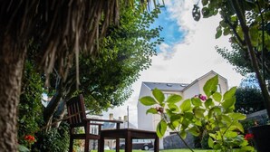 A garden with two wooden chairs, a white building, and a car in the background. - Richmond Hotel (Aberystwyth)