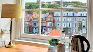 A room with a large window, a lamp, a kettle, and a tray with cups and a bag. - Richmond Hotel (Aberystwyth)