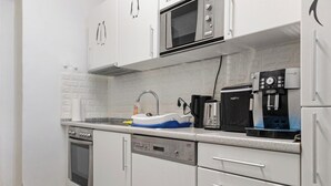A modern kitchen with white cabinets, a microwave, a coffee machine, and a dishwasher. - Luxury 6BR Apt near Millennium City (Vienna)