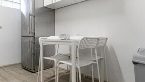 A small kitchenette with a stainless steel refrigerator, a white table with two chairs, and a trash bin. - Luxury 6BR Apt near Millennium City (Vienna)