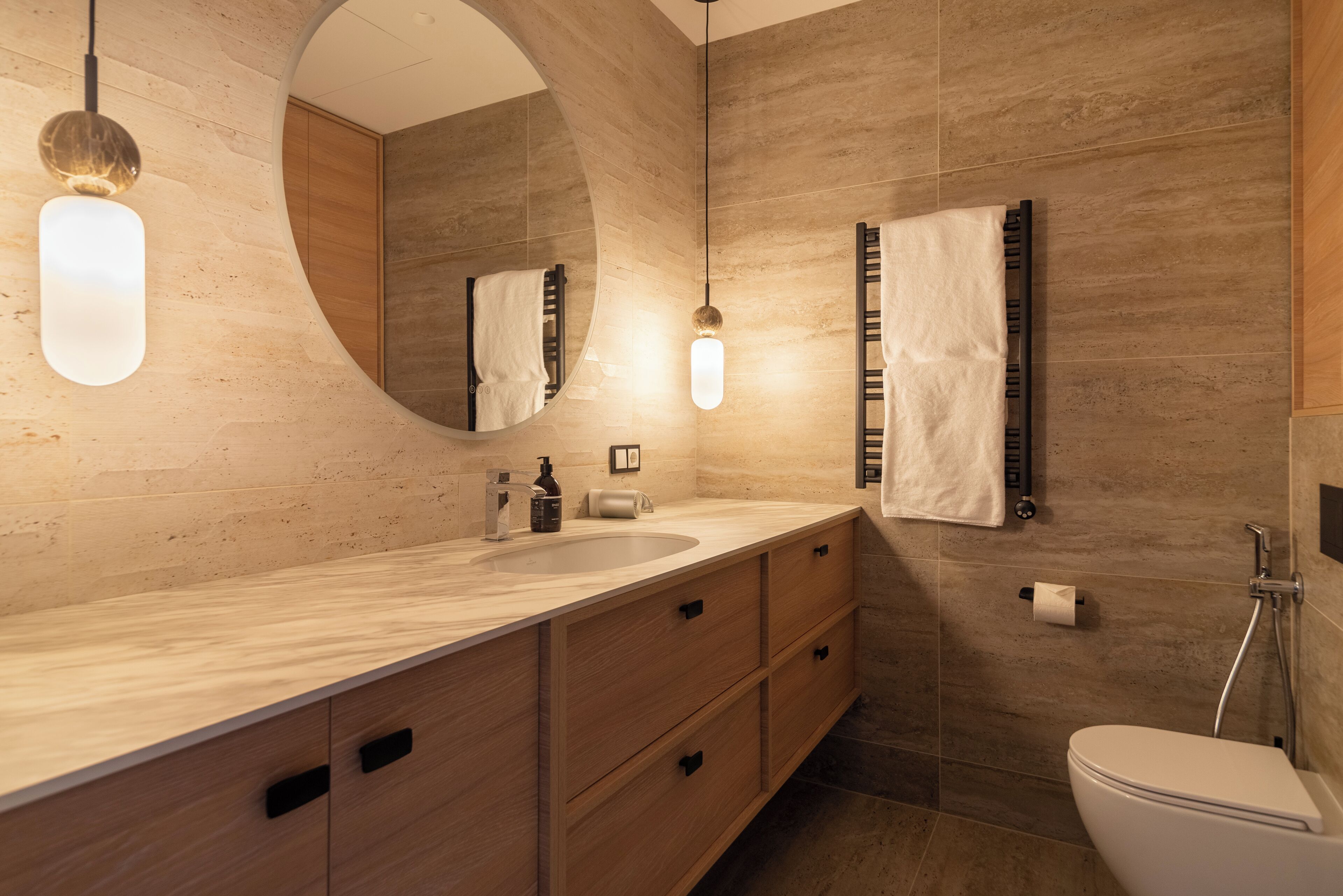 A modern bathroom with a large mirror, wooden vanity, and a shower.