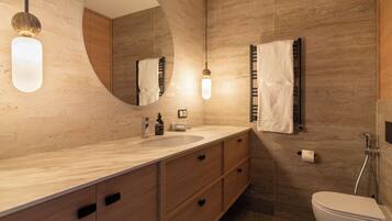 A modern bathroom with a large mirror, wooden vanity, and a shower.