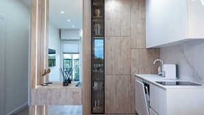 A modern kitchen with a built-in dishwasher, a small countertop, and a window overlooking a balcony. - Nemunas Aparthotel (Druskininkai)