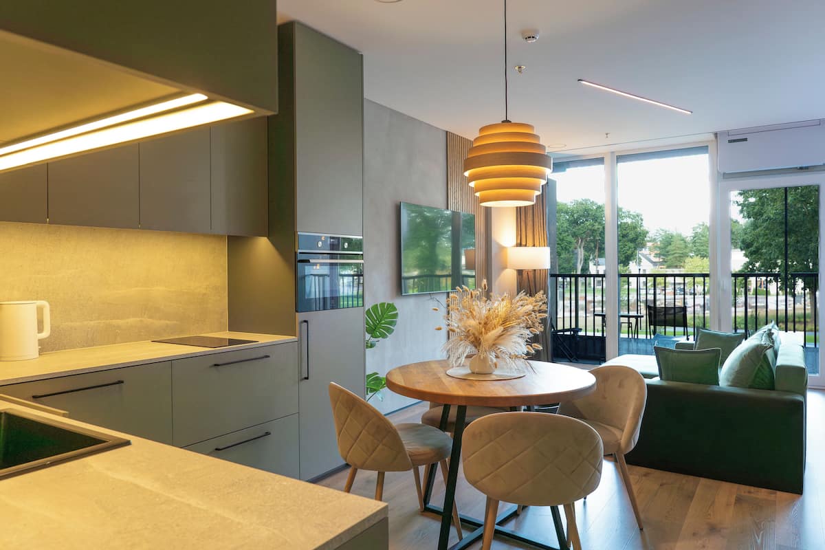 Een moderne keuken met een eethoek, grote ramen en een groene bank.