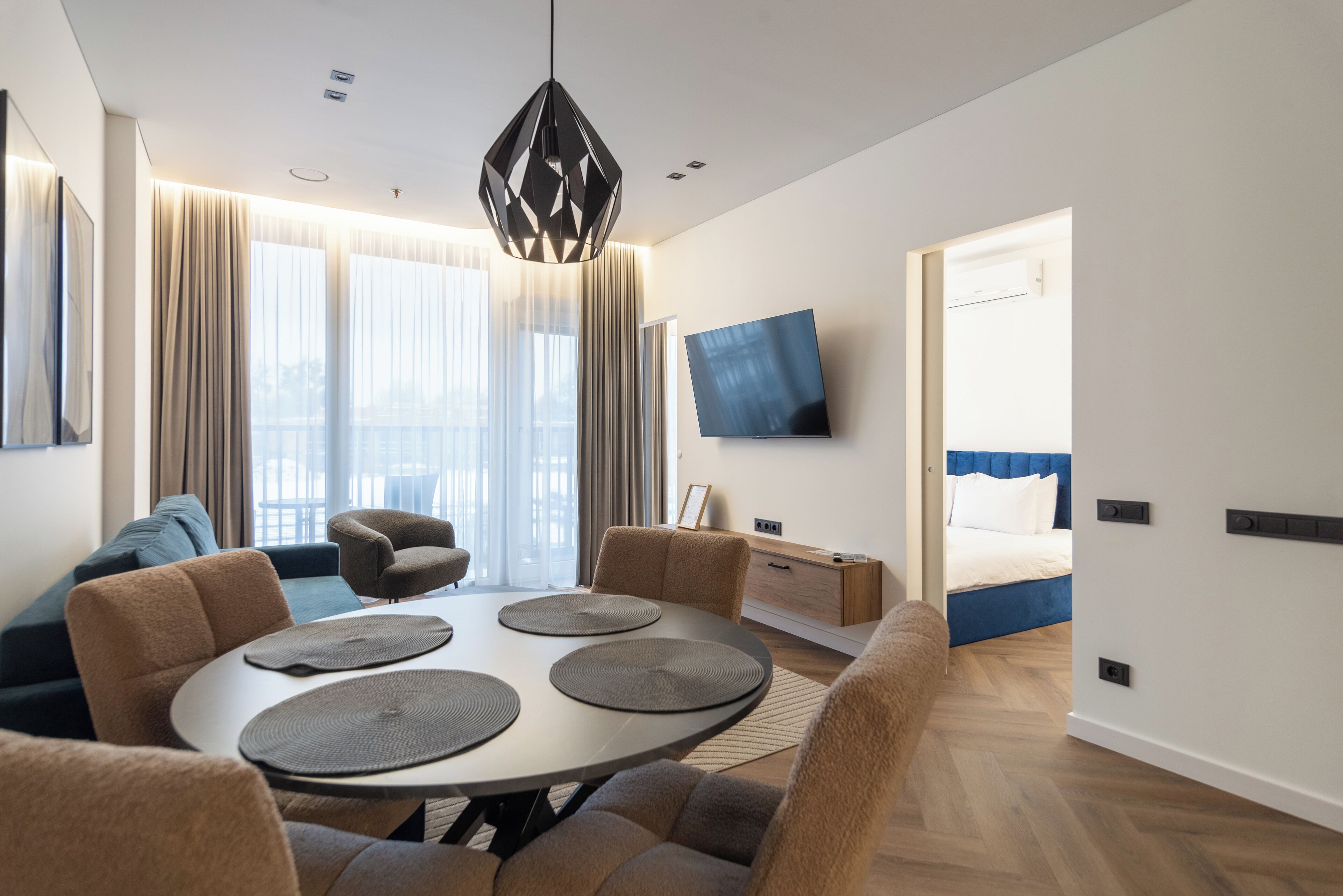 Een moderne hotelkamer met een zithoek, een bed, een televisie en uitzicht over de stad.