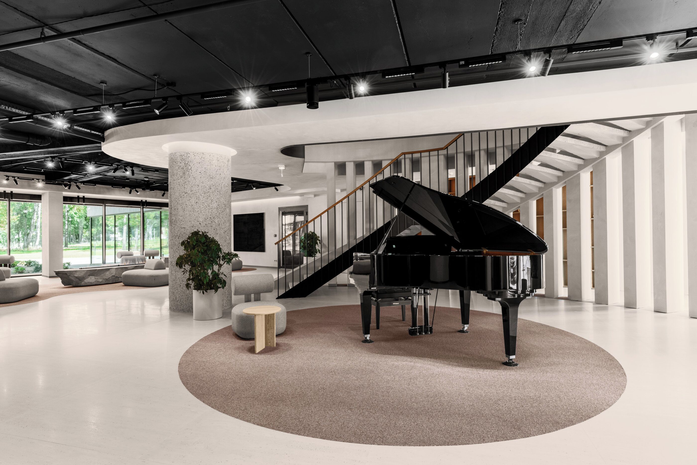 A spacious lobby with a grand piano, a staircase, and a large column.