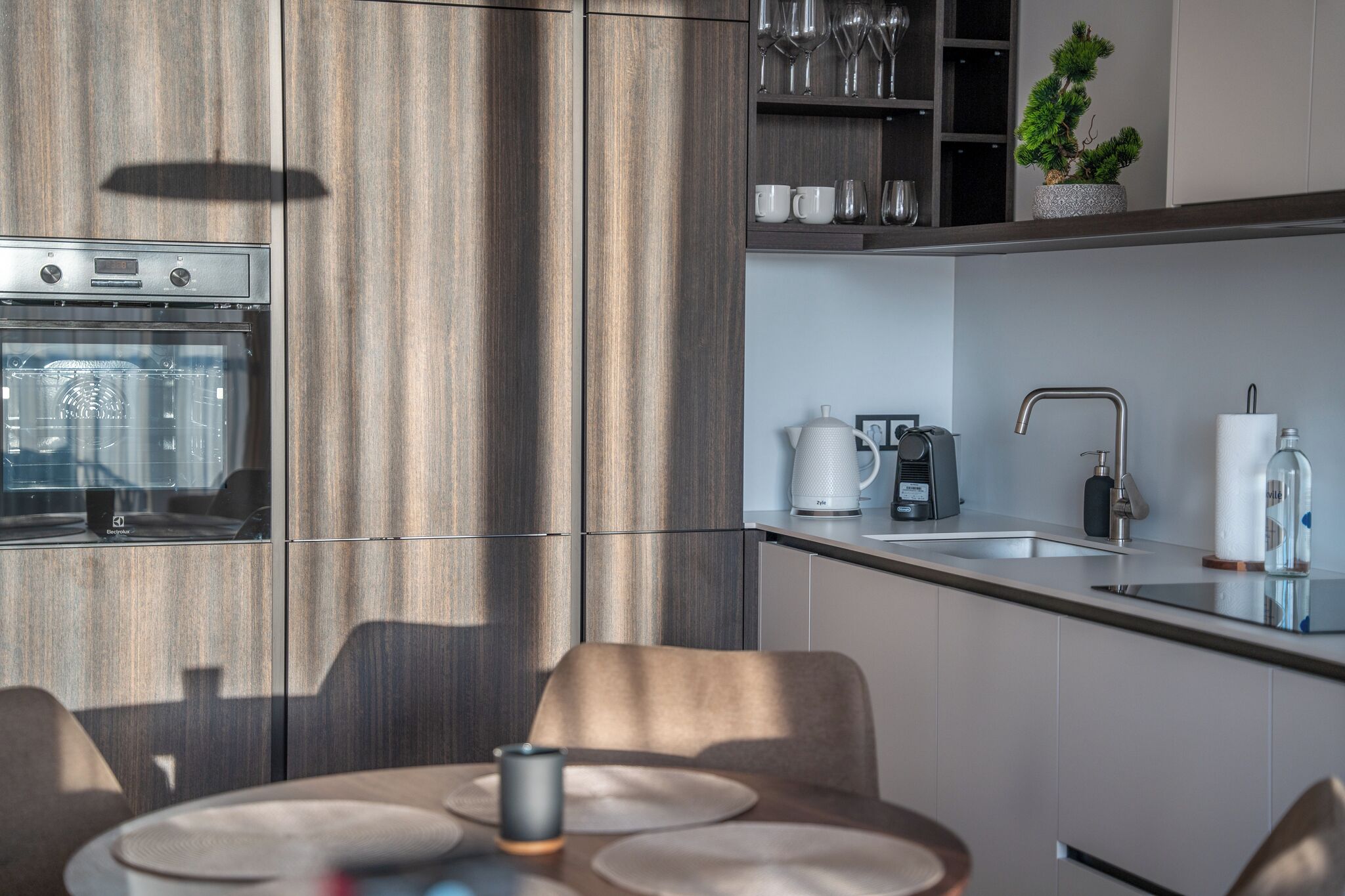 Una cocina moderna con horno empotrado, cafetera y pileta.
