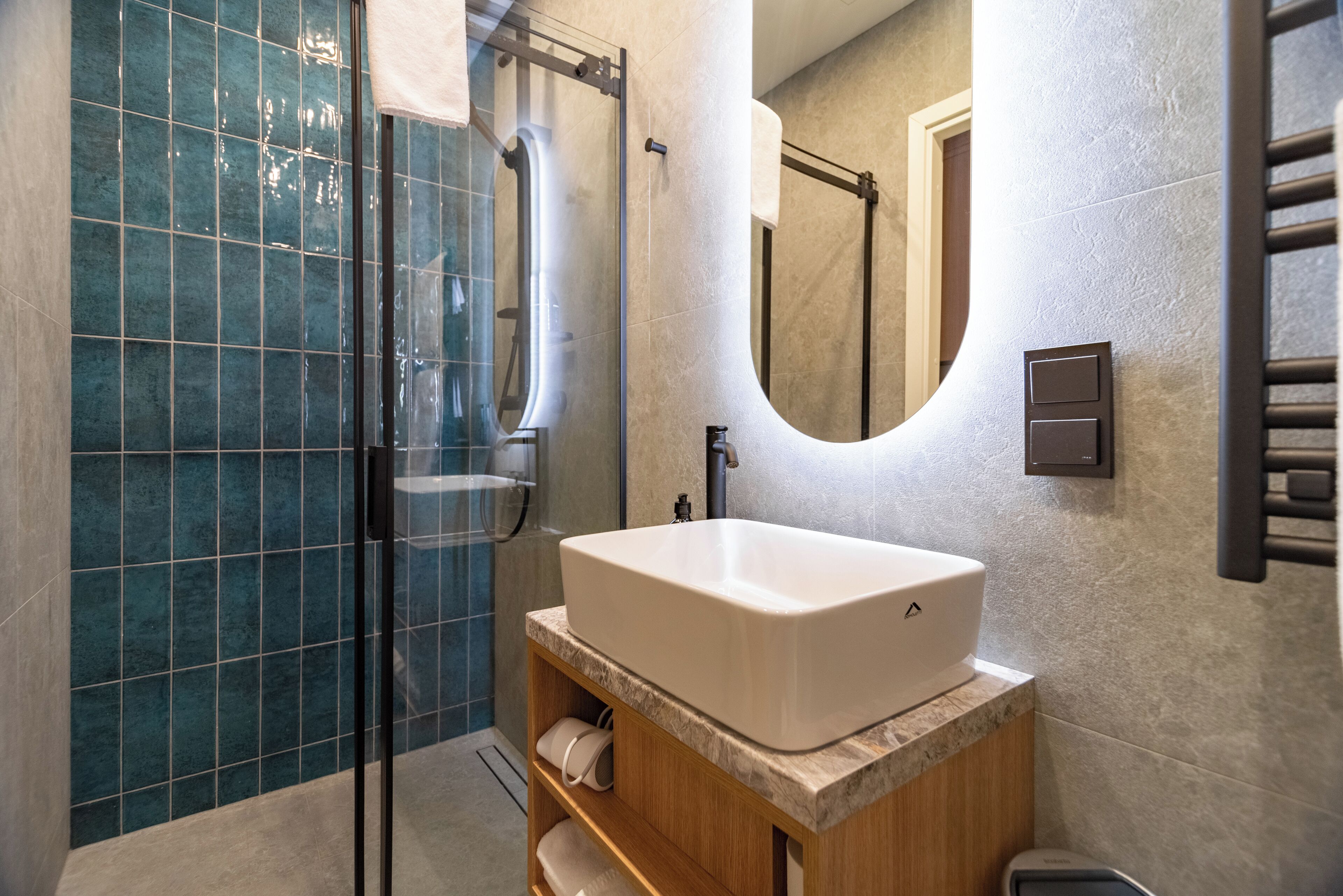 A modern bathroom with a glass shower enclosure, a large sink, and a wooden vanity.
