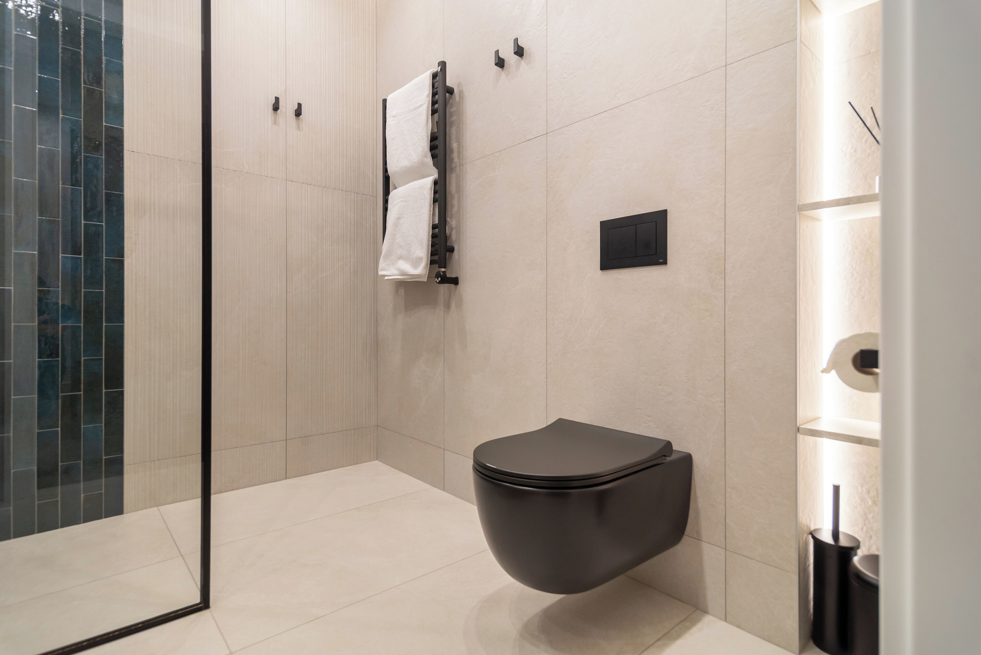 Un baño moderno con inodoro, toallero y cabina de ducha de vidrio.