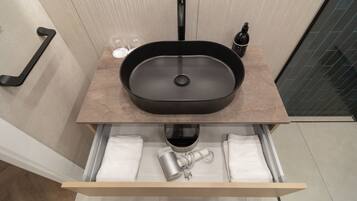 A bathroom with a modern sink, a towel rack, and a towel warmer.