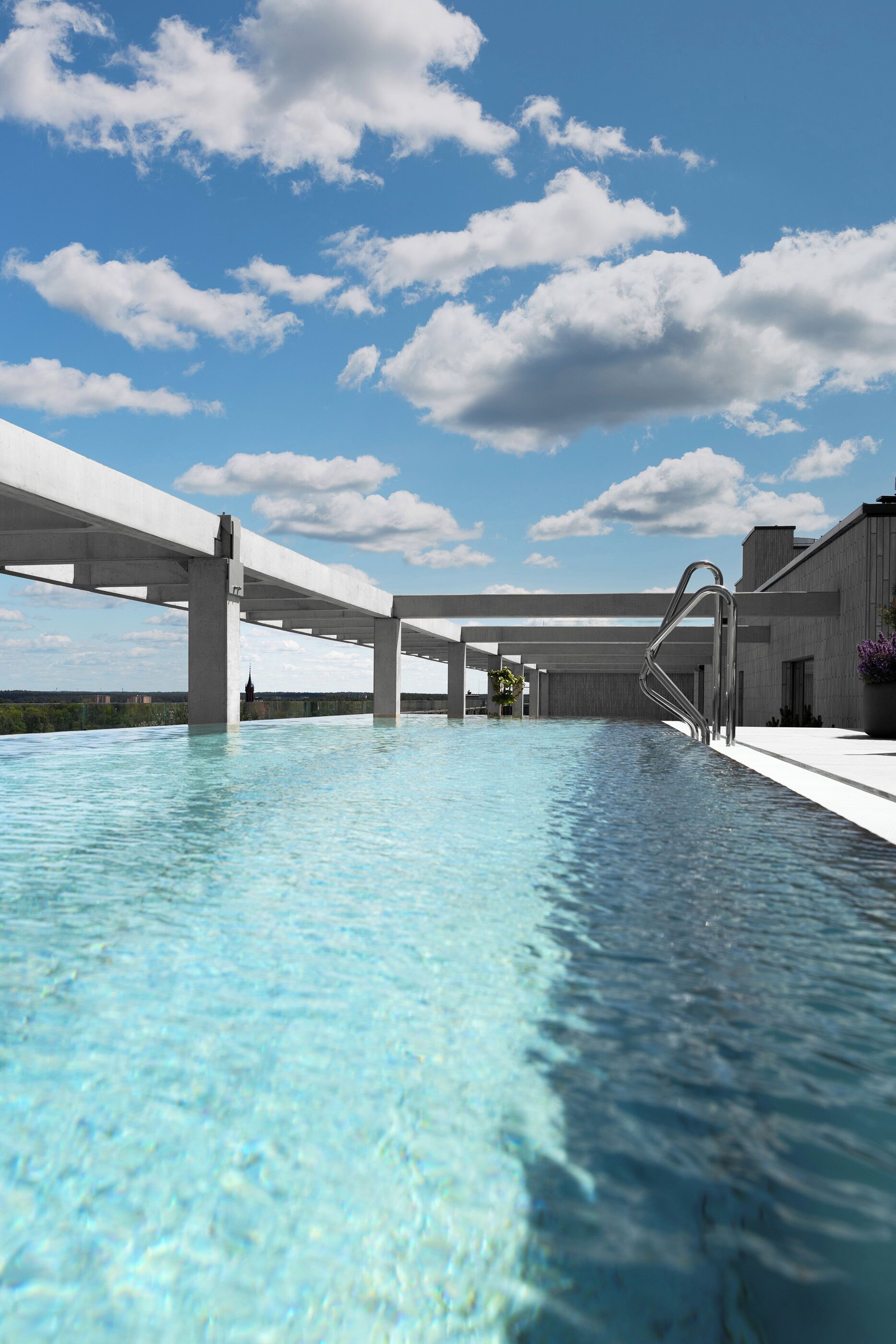 Una piscina moderna con agua cristalina, rodeada por un solado de hormigón y sostenida por robustas columnas de hormigón.