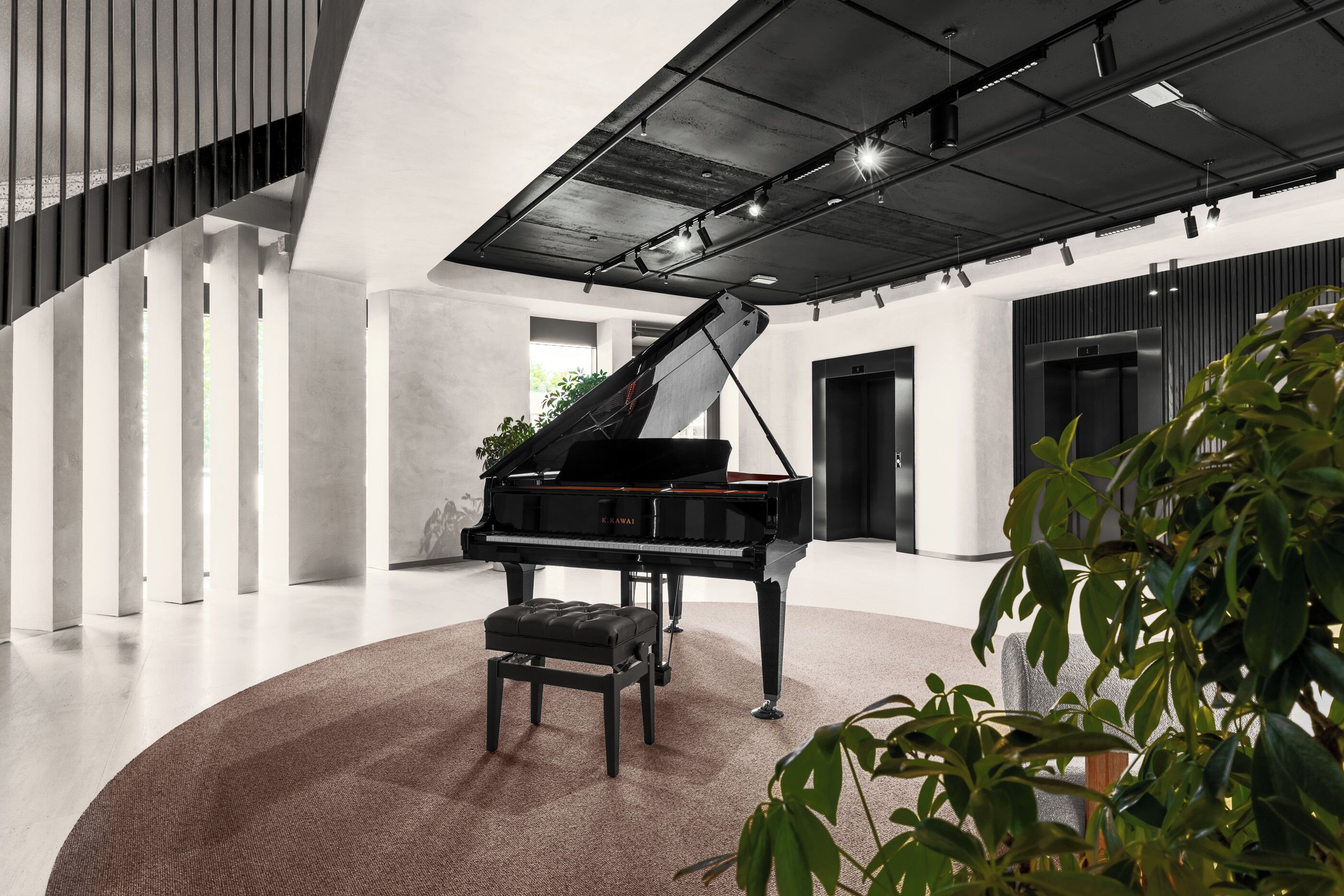 Un piano de cola en un interior moderno y espacioso, con techos altos y una alfombra circular.