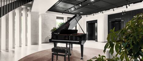 Un piano de cola en un interior moderno y espacioso, con techos altos y una alfombra circular.