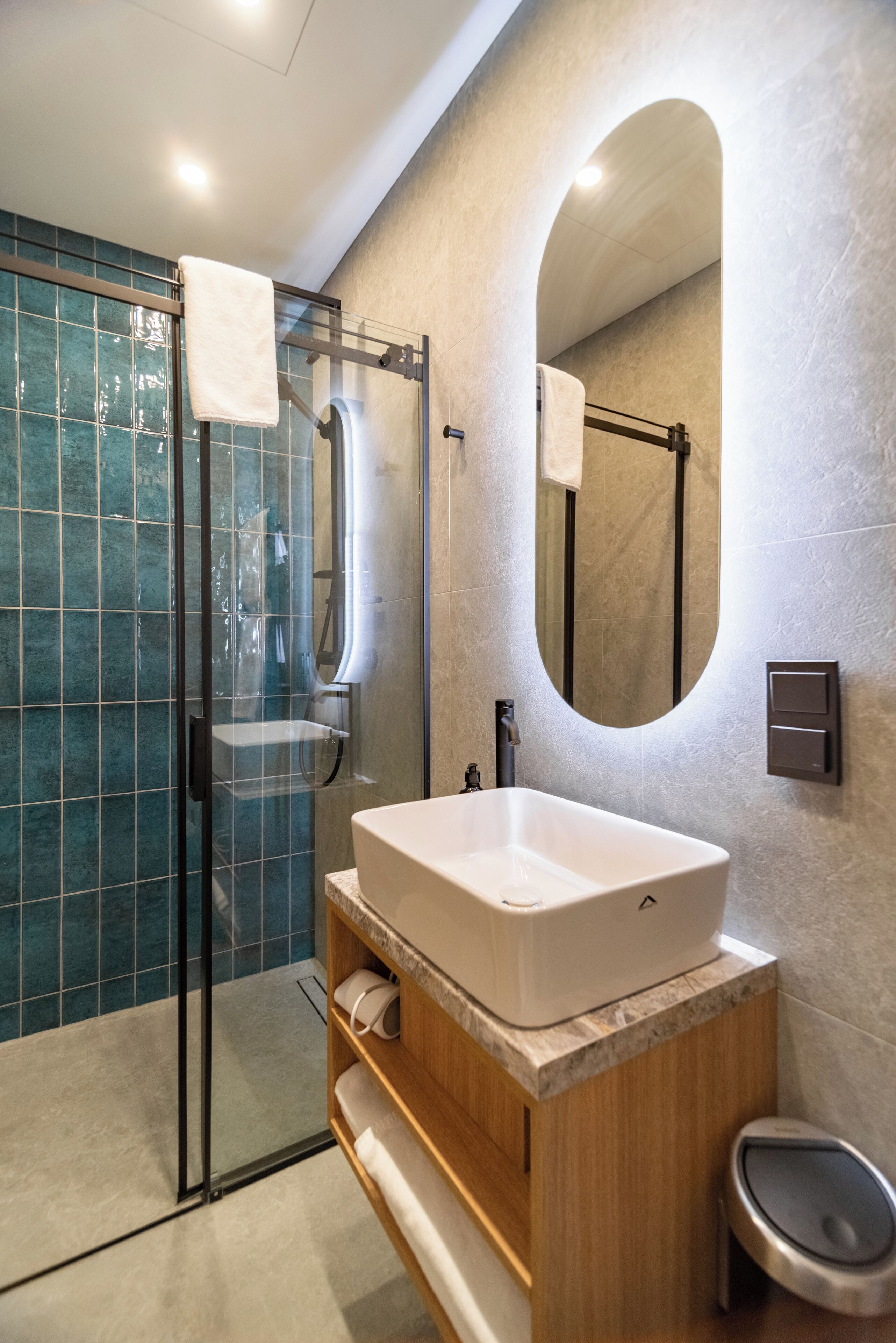 Un baño moderno con ducha de vidrio, un espejo grande y un tocador de madera con lavabo.