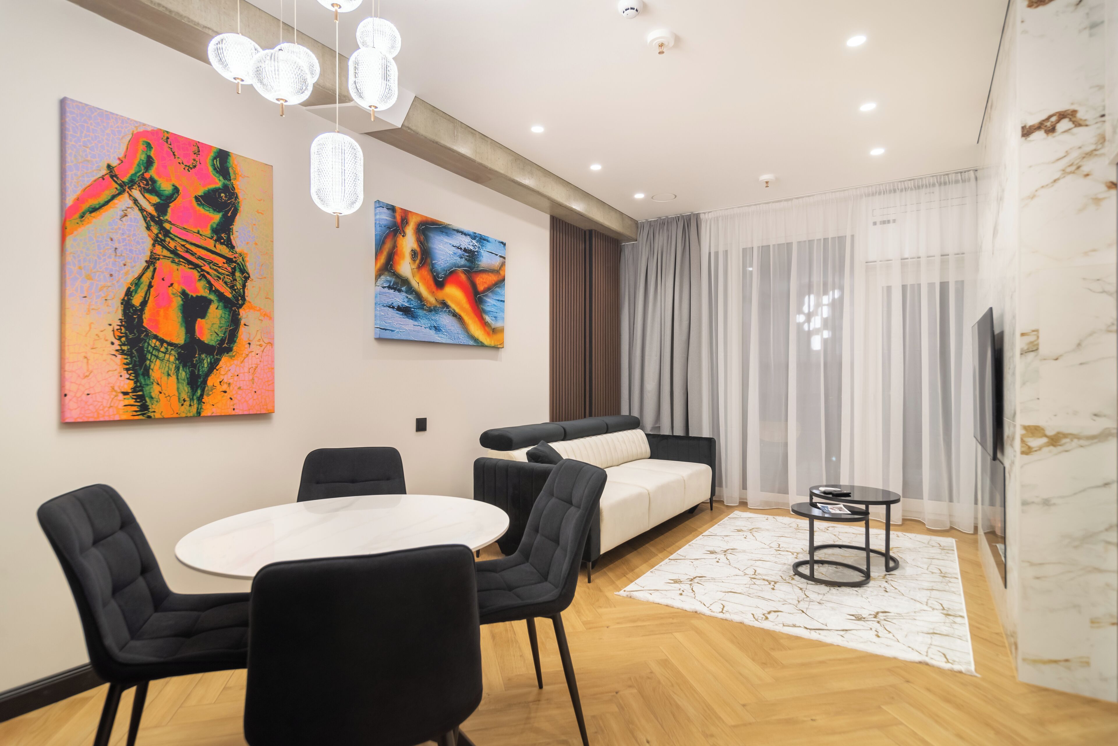 Una sala de estar moderna con un sofá, una mesa de comedor con sillas y obras de arte en las paredes.