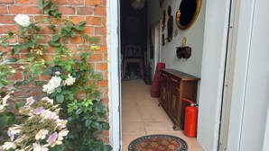 A doorway leading to a room with a tiled floor, a doormat, and a brick wall.