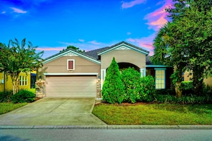 A residential house with a garage, a well-maintained lawn, and mature trees. - 20 min to Disney , Epic , Star Wars , Gameroom ,Pool Luxe dw7 (Davenport)