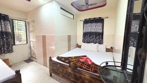 A bedroom with a bed, a ceiling fan, a window with curtains, and a door. - Swastika Inn Old Digha AC Non AC Rooms (Digha)