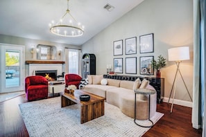 Una sala de estar con chimenea, sillones rojos, un sofá color crema y cuadros enmarcados en la pared.