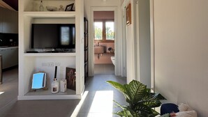 Ein modernes Wohnzimmer mit Fernseher, Bücherregalen, Couchtisch und einer Pflanze.