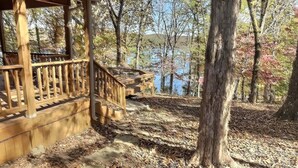 A wooden gazebo with a wooden deck and railing, surrounded by trees and a lake. - Private Beaver Lake front Escape | 50 Acres (Rogers)