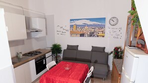 Eine kleine Küche mit Essbereich, einer Couch und einer Wanduhr.