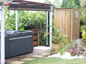 A hot tub under a pergola, a wooden shed, and a garden with plants and flowers. - Authentic Creole Room in Les Avirons (Les Avirons)