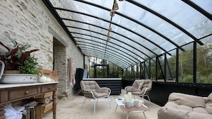Eine überdachte Terrasse mit Steinmauer, Korbmöbeln und einem für das Essen gedeckten Tisch.
