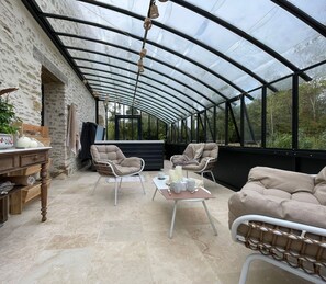 Un patio techado con pared de piedra, mobiliario de mimbre y una mesa lista para comer.
