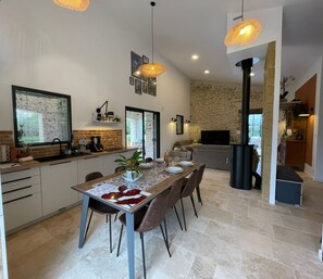 Una cocina moderna con comedor, que incluye una isla grande, lámparas colgantes y un salpicadero de piedra.