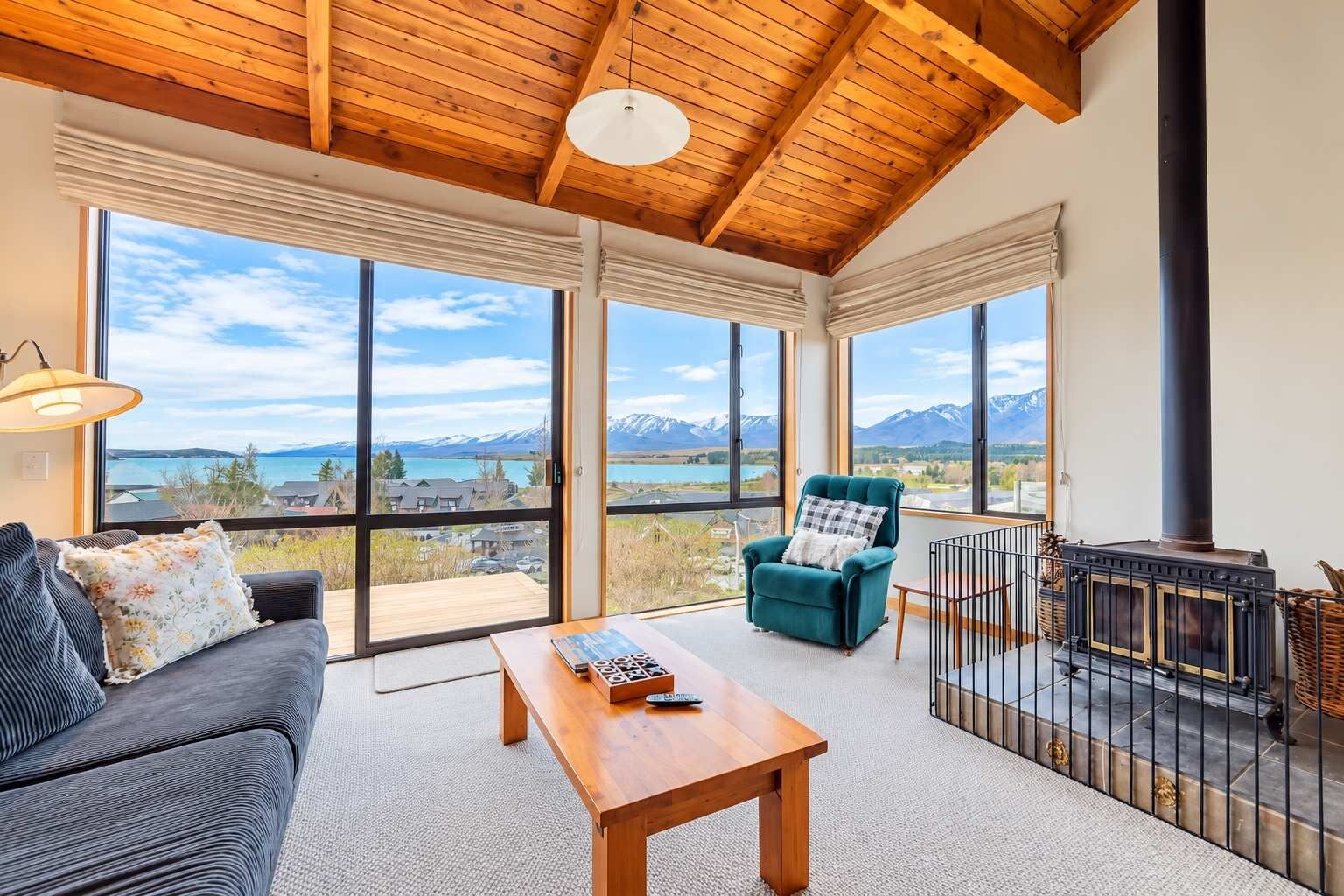 A spacious room with a large window, a cozy sofa, a wooden table, and a fireplace.