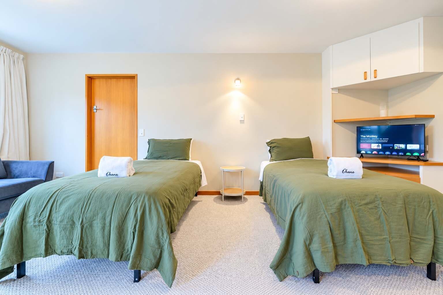 A hotel room with two beds, a television, a small table, and a wardrobe.