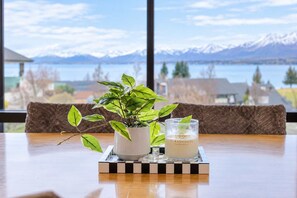 Ein Tisch mit einer Topfpflanze und einer Kerze, vor einem Fenster mit Blick auf die Berge.