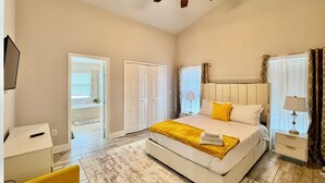 Um quarto com uma cama grande, um ventilador de teto, uma escrivaninha e uma cadeira.