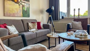 Una sala de estar moderna con un sofá gris, una mesa redonda de centro y una lámpara de pie.